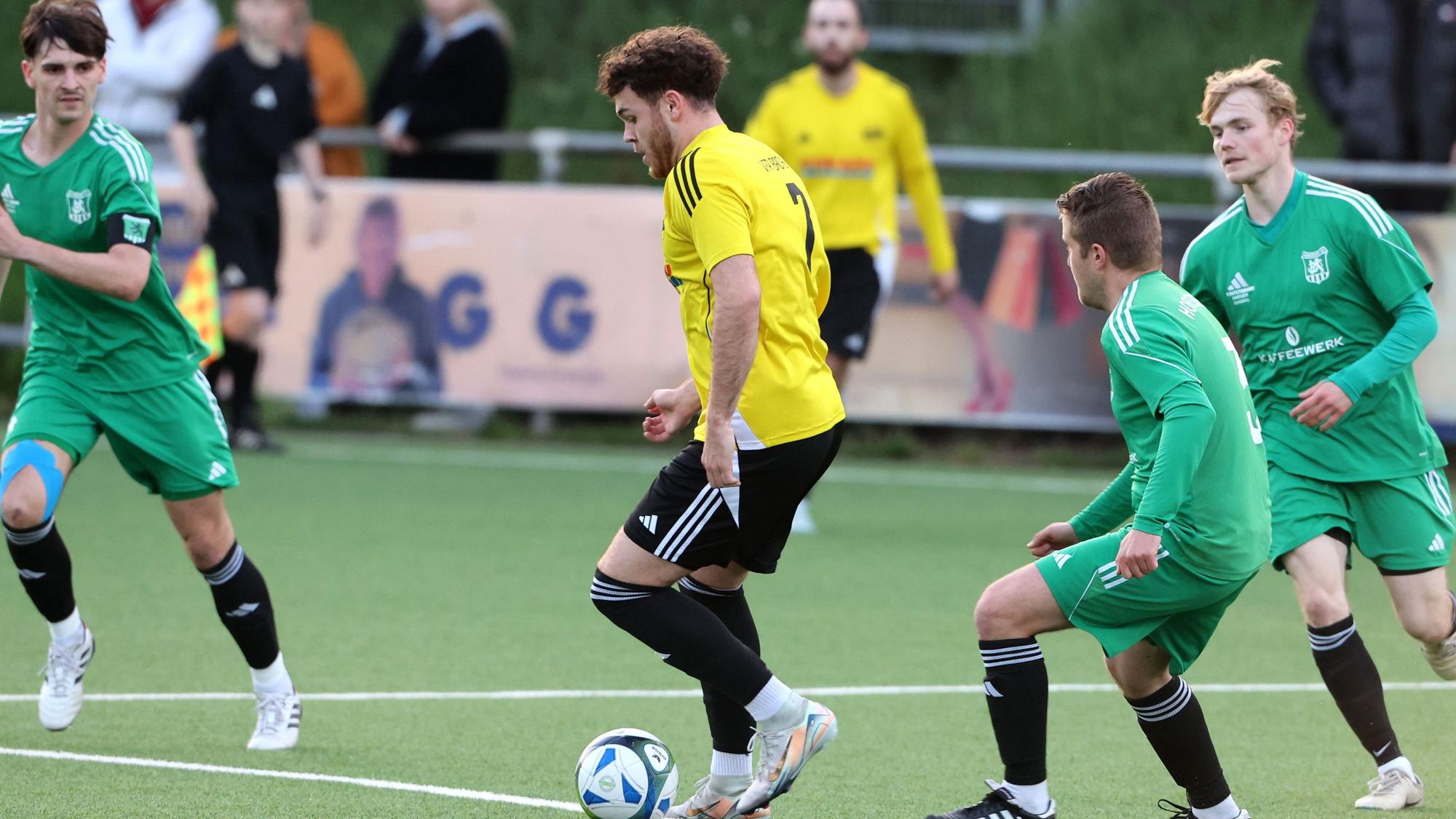 Das Foto zeigt einen Bachemer Spieler im hellen Trikot, der von drei Horremern umringt wird.