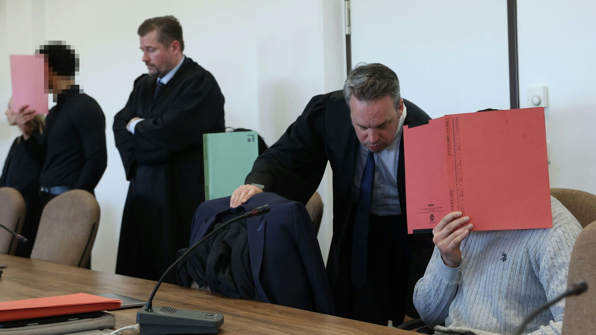 Die drei Angeklagten mit ihren Verteidigern beim Prozessauftakt im Kölner Landgericht