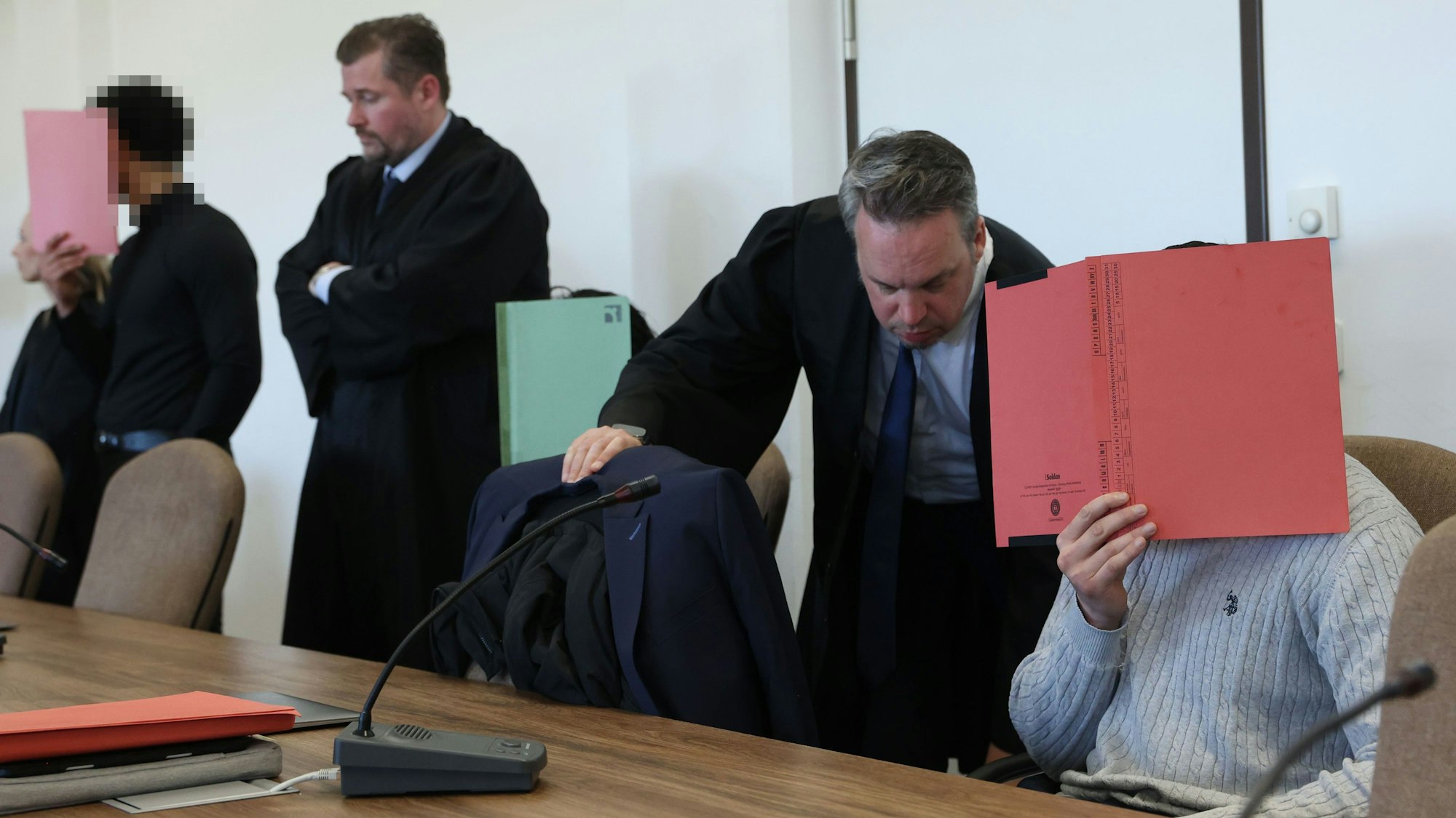 Die drei Angeklagten mit ihren Verteidigern beim Prozessauftakt im Kölner Landgericht