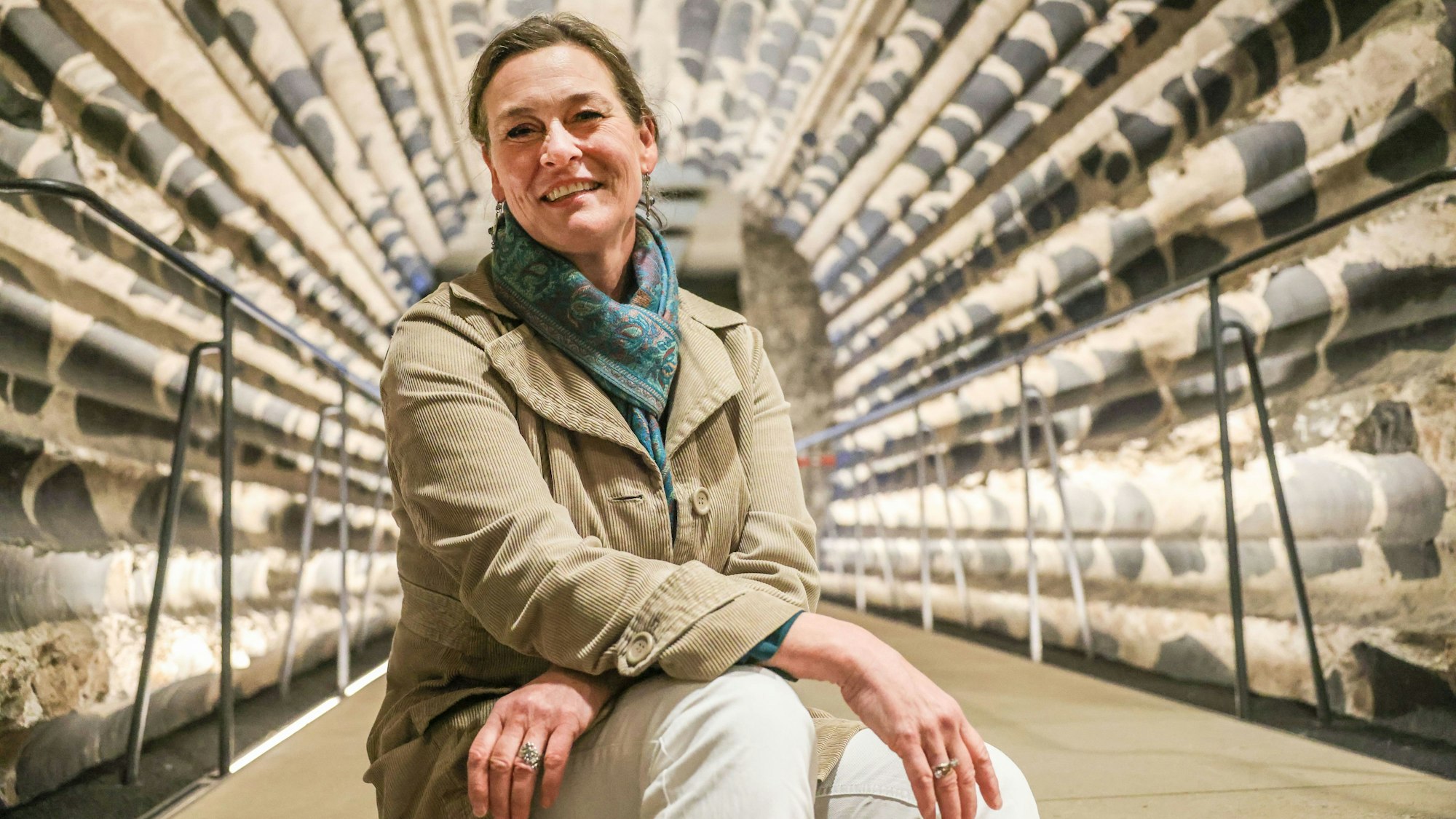 PRODUKTION - 31.03.2025, Nordrhein-Westfalen, Köln: Ruth Stinnesbeck, Archäologin am Dom, sitzt im Gang zur Ausgrabung unter dem Fundament des Domes. (zu dpa: «Gräber, Gold und Gullys - Expedition unter den Kölner Dom») Foto: Oliver Berg/dpa +++ dpa-Bildfunk +++