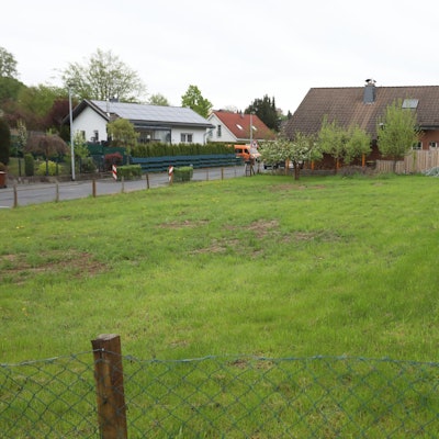 Eine Rasenfläche mit Wohngebäuden im Hintergrund.