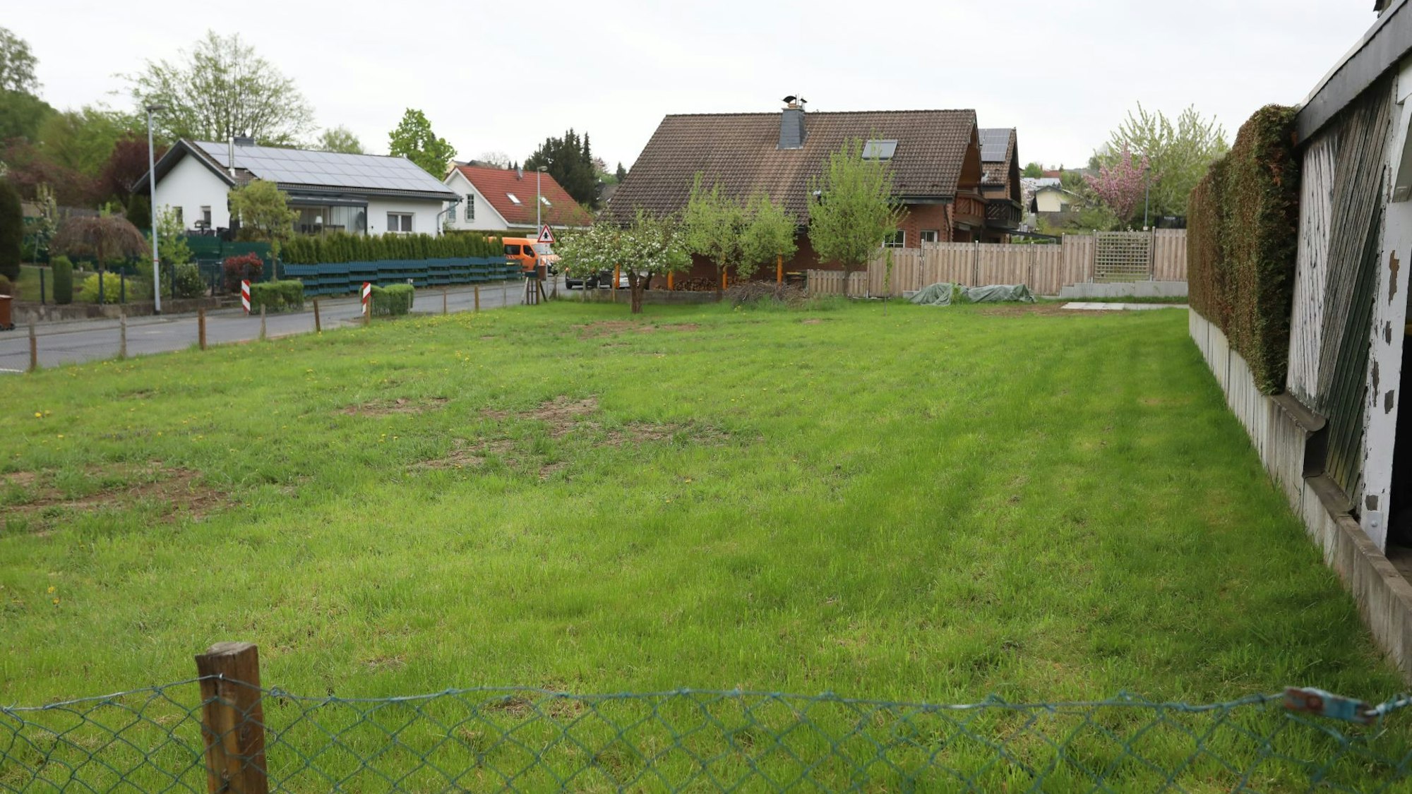 Eine Rasenfläche mit Wohngebäuden im Hintergrund.