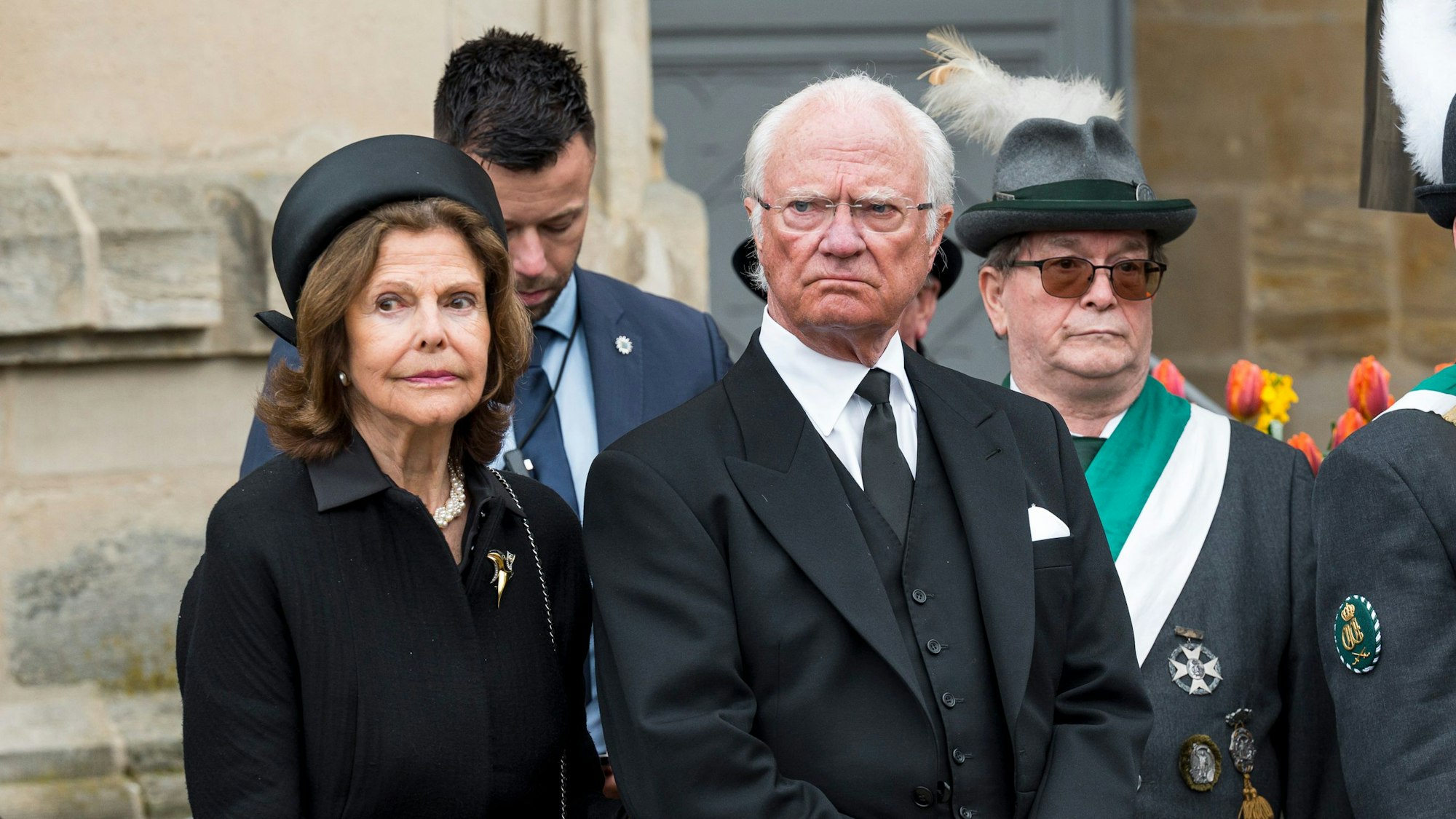 Königin Silvia von Schweden (l) und der Schwedische König Carl XVI. Gustaf (m) stehen während der Trauerfeier für Prinz Andreas von Sachsen-Coburg und Gotha auf dem Schlossplatz.