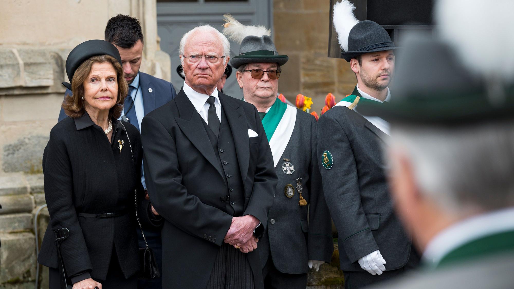 Königin Silvia von Schweden (l) und der Schwedische König Carl XVI. Gustaf (M) stehen während der Trauerfeier für Prinz Andreas von Sachsen-Coburg und Gotha auf dem Schlossplatz.