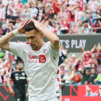 Ein Fußballspieler schlägt seine Hände über dem Kopf zusammen.