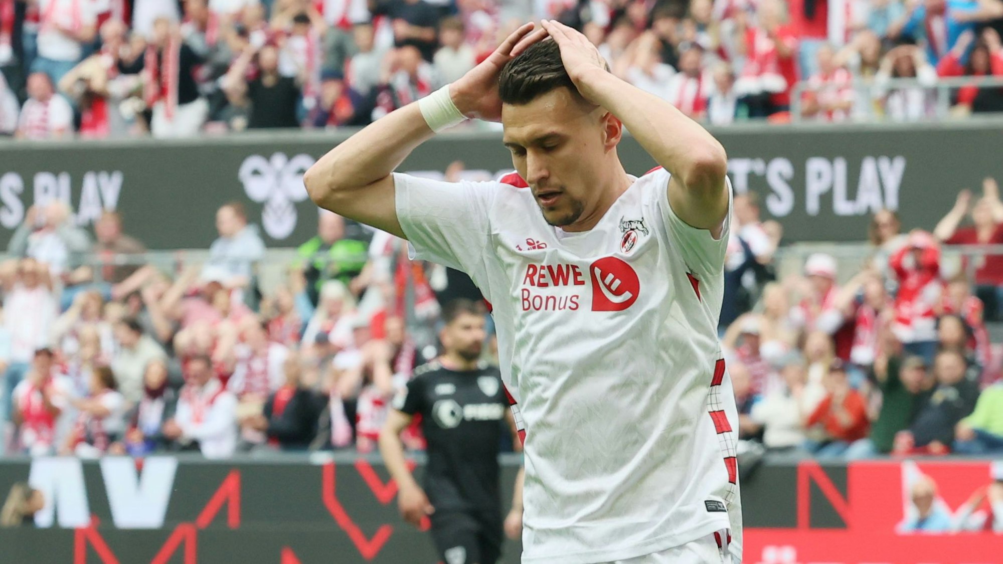 Ein Fußballspieler schlägt seine Hände über dem Kopf zusammen.