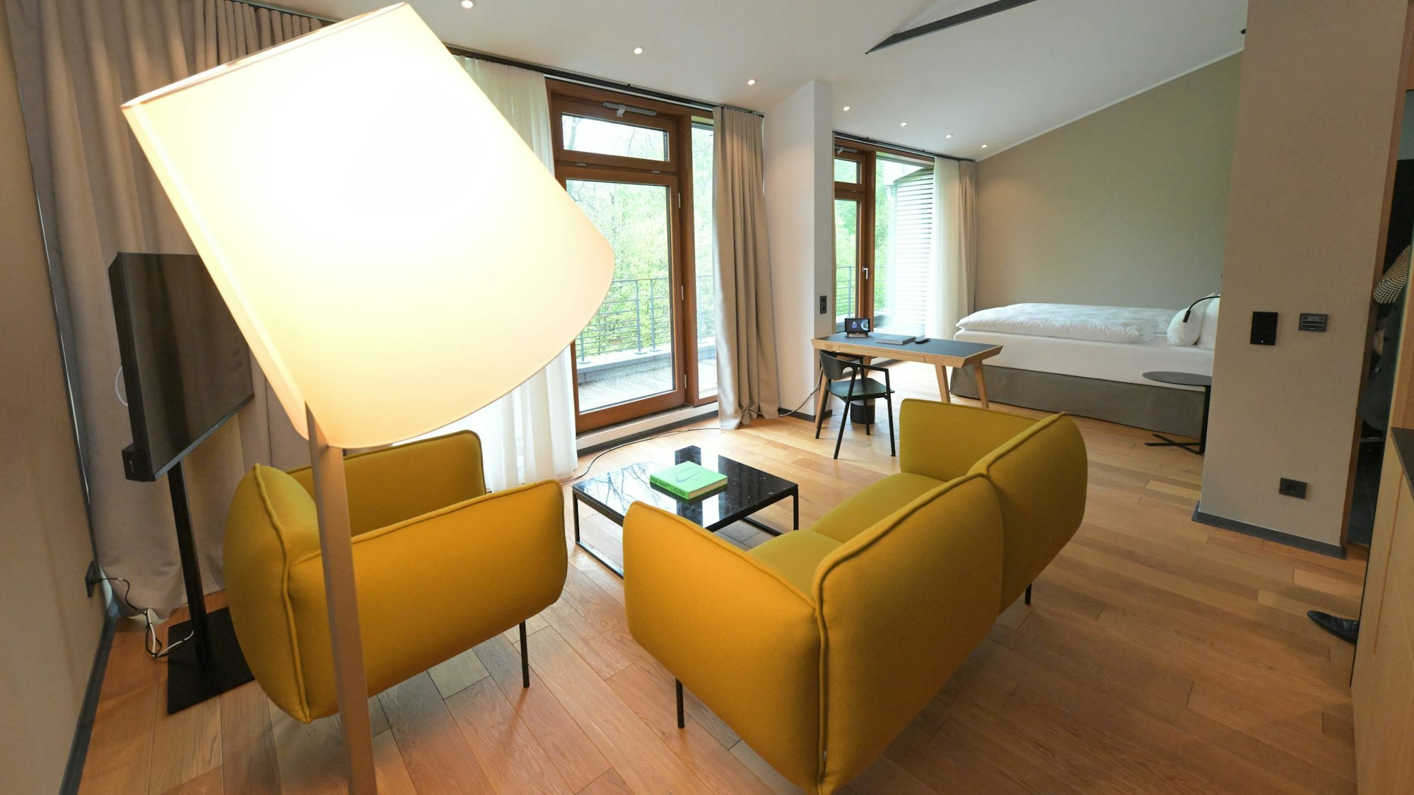 In einem Zimmer mit Waldblick steht eine gelbe Couch.