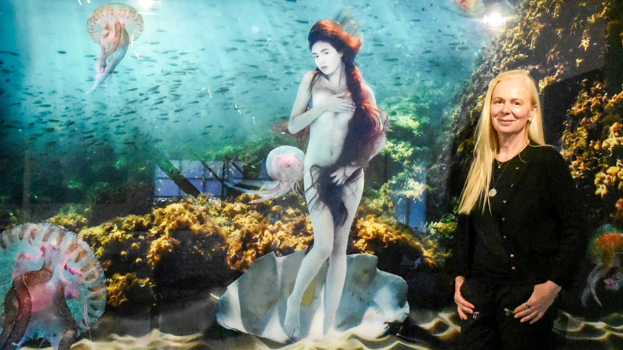 Eine Frau steht vor einem Bild, einer Unterwasser-Komposition von Botticellis Venus.