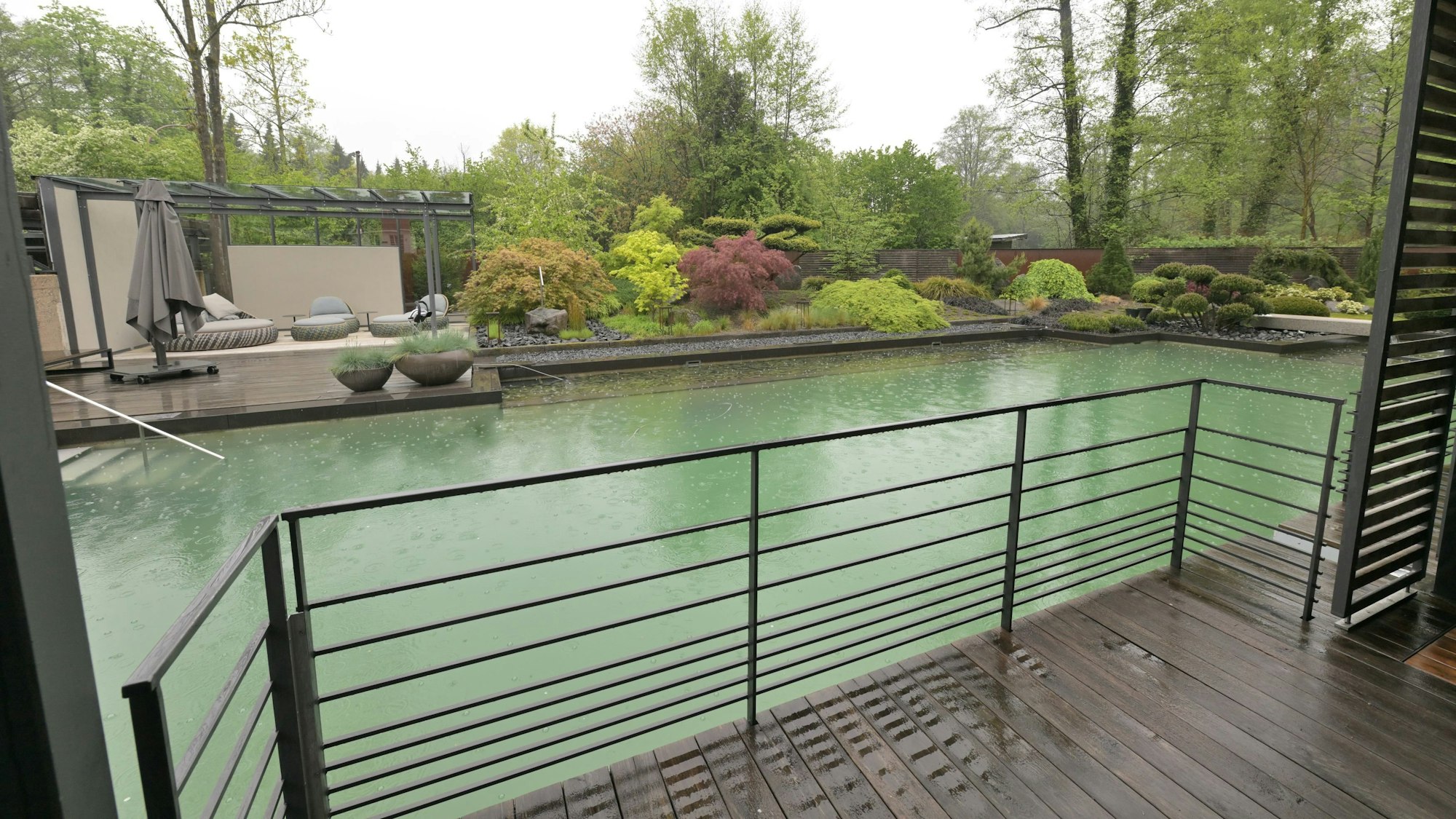 Hinter einem Balkon liegt ein Pool.