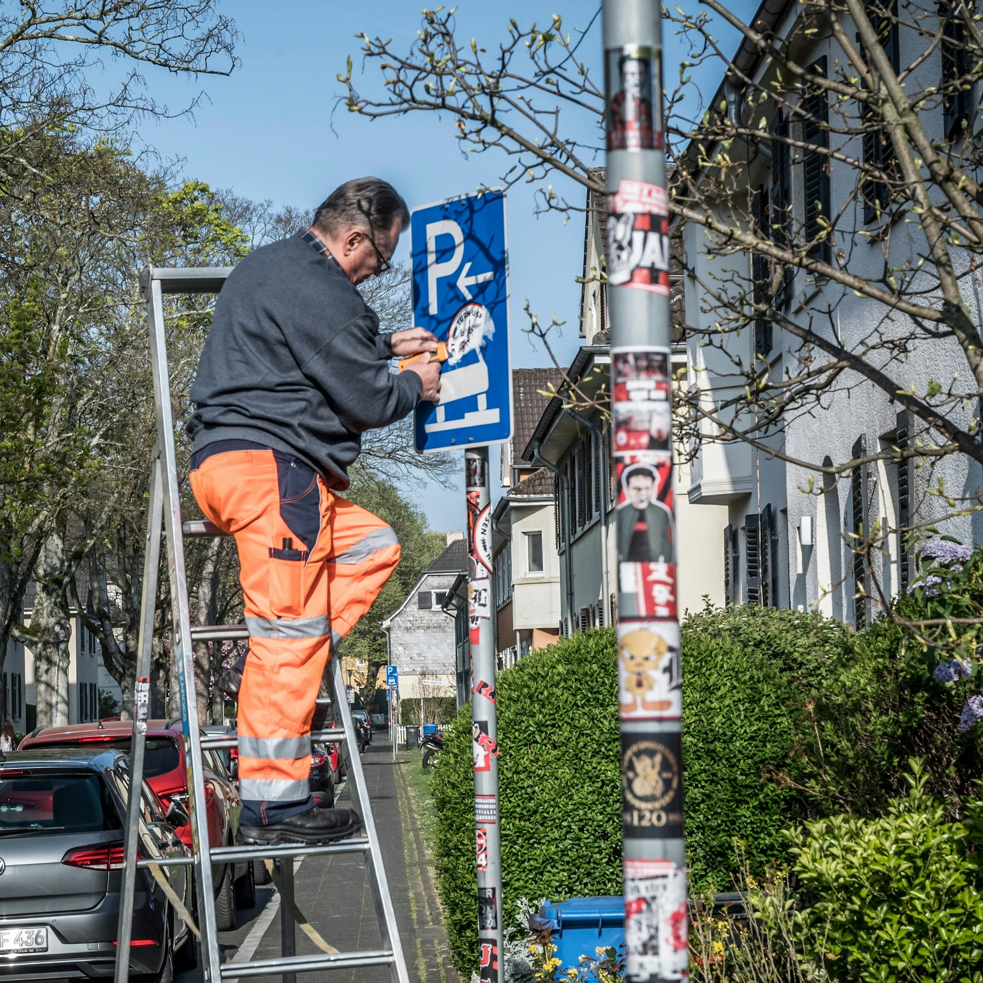 TBL-Mitarbeiter beim Entfernen von Aufklebern der Fußball-Ultras von verkehrsschildern in der Kolonie III. Foto: Ralf Krieger