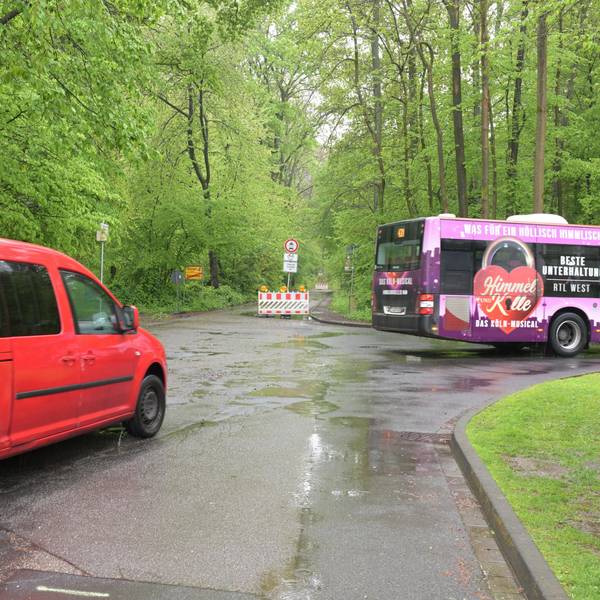 Ein Bus und ein Auto biegen vor einer Straßensperre nach rechts ab.