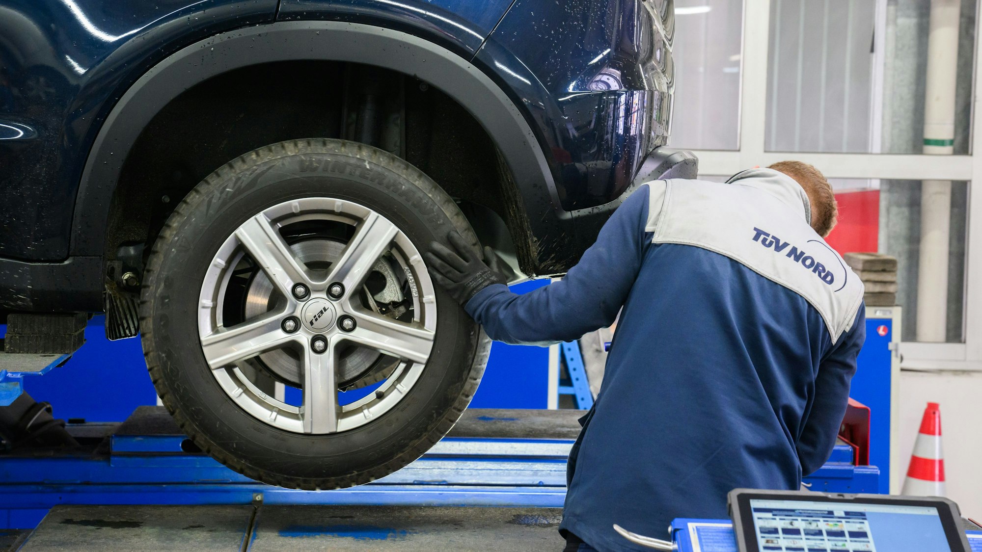 Ein TÜV-Prüfer begutachtet ein Auto bei der Hauptuntersuchung.