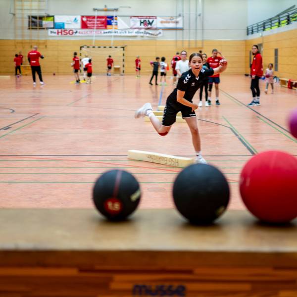 Ein Mädchen versucht, mit einem Ball andere Bälle zu treffen.