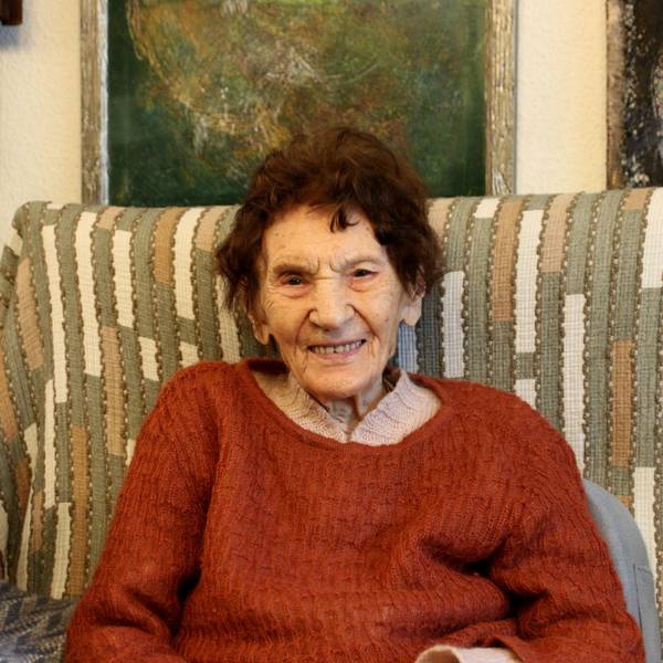 Eine 101-jährige Frau sitzt auf einem Sofa.