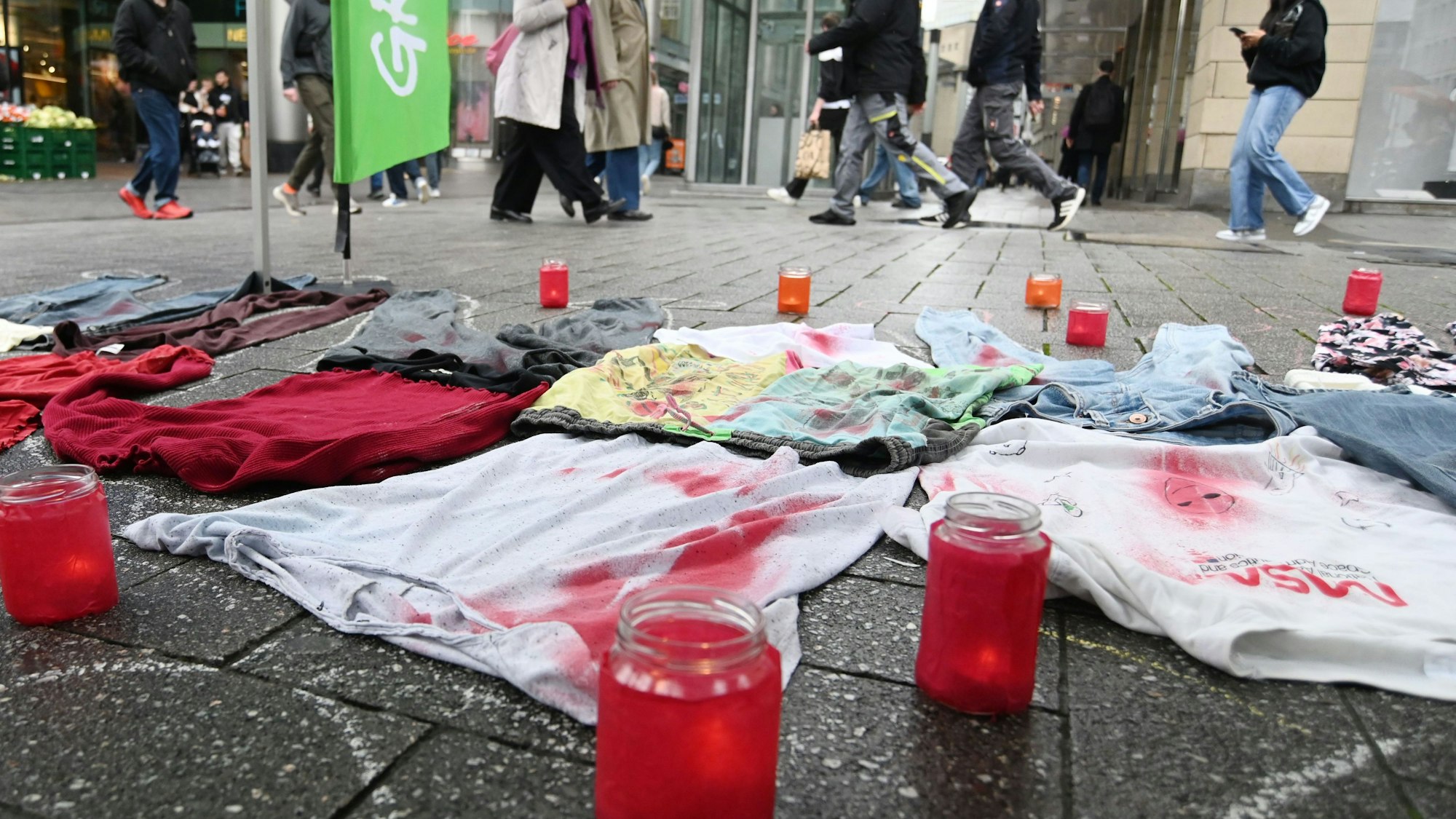 Das Foto zeigt Grabkerzen und künstlich blutverschmierte Kleidungsstücke.