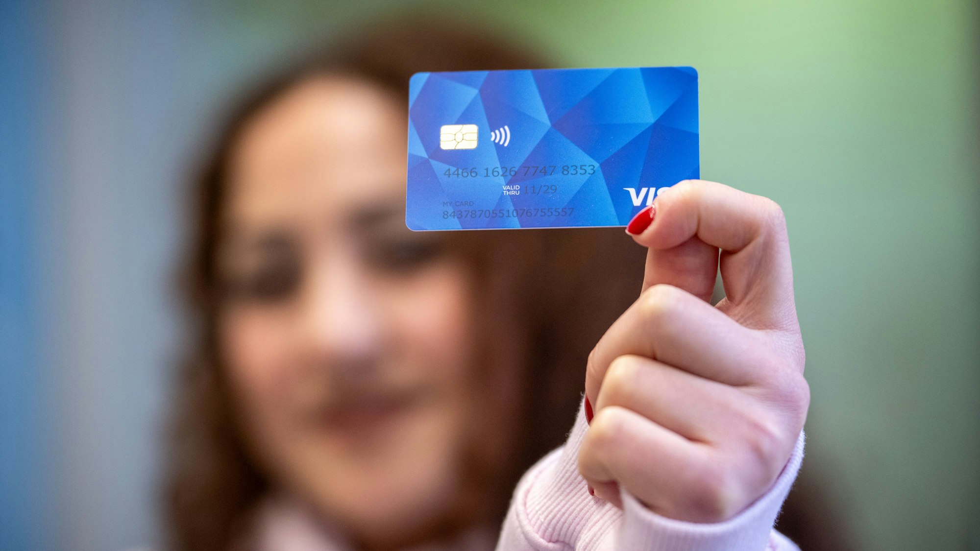 Eine Person hält eine blaue Karte mit Chip in die Kamera.
