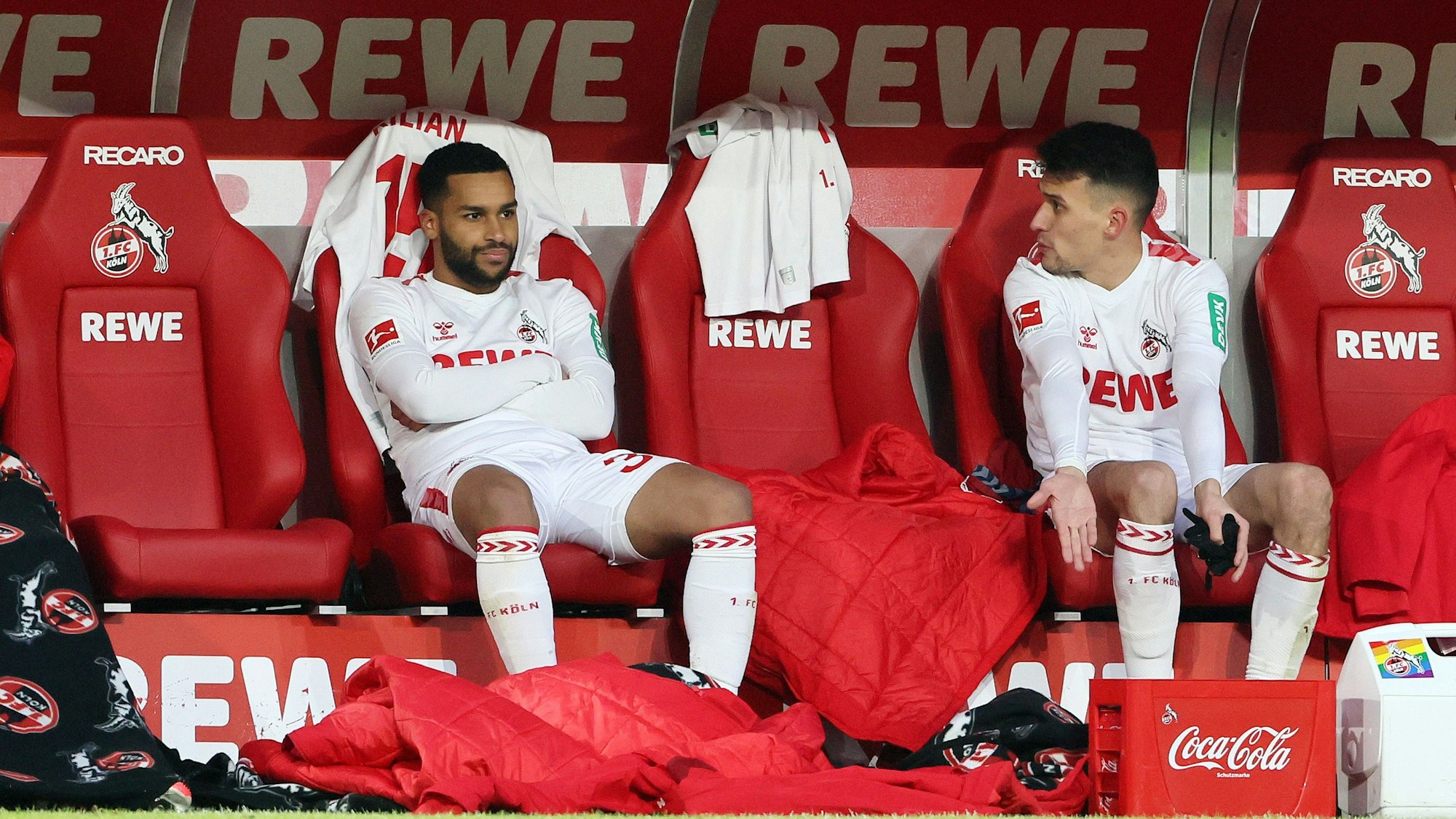 Linton Maina (l.) und Dejan Ljubicic vom 1. FC Köln sitzen gemeinsam auf der Kölner Bank. Die sportliche Zukunft beider FC-Profis ist aktuell noch offen.