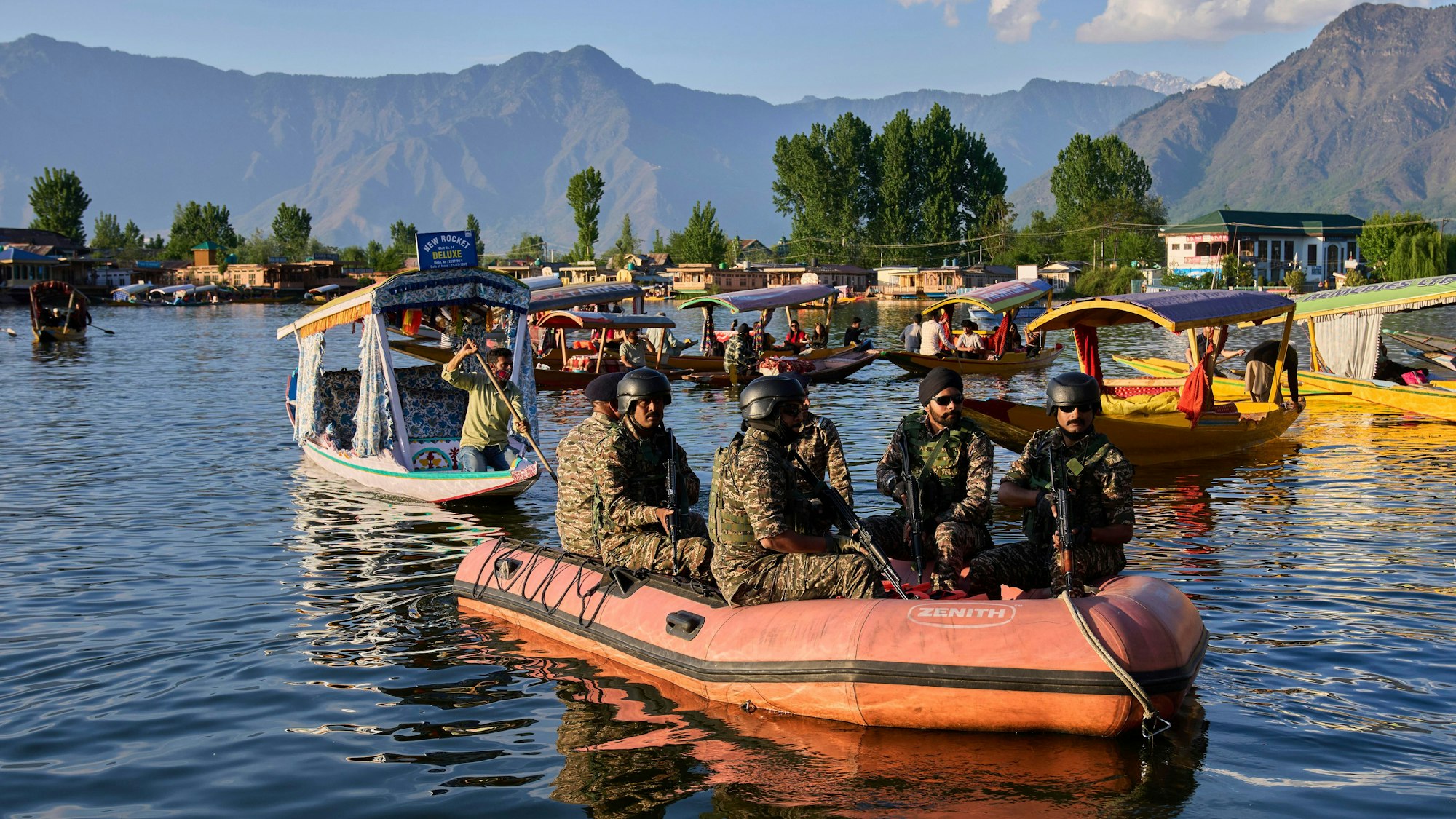 Paramilitärische Soldaten patrouillieren auf einem Schlauchboot, während indische Touristen eine Bootsfahrt unternehmen.