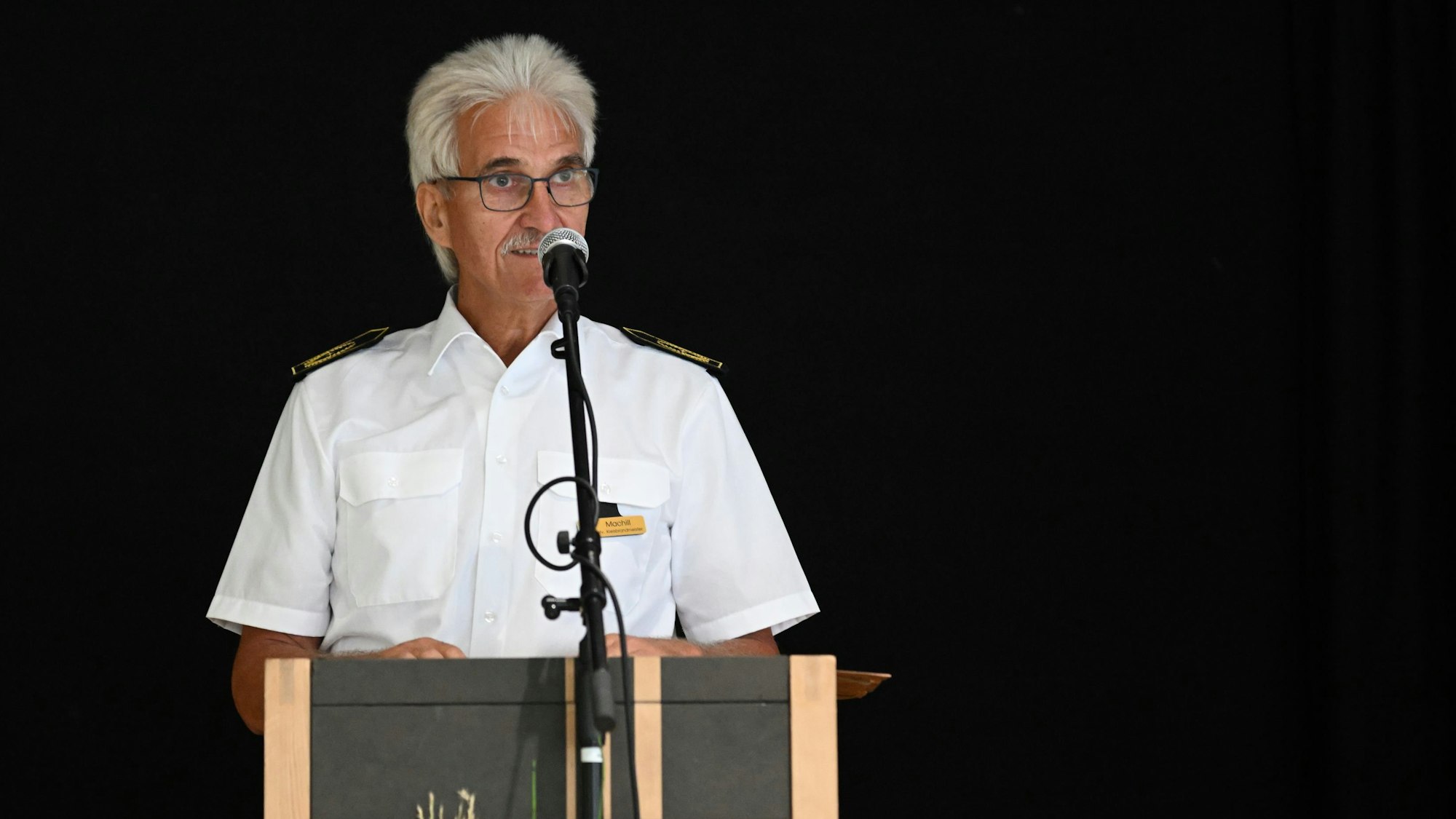 Rhein-Bergs stellvertretender Kreisbrandmeister Roger Machill
steht an einem Rednerpult und spricht.