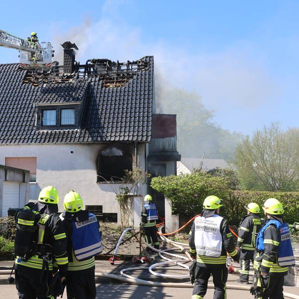 Mehrere Feuerwehrleute löschen, auch per Drehleiter, einen Wohnhausbrand.