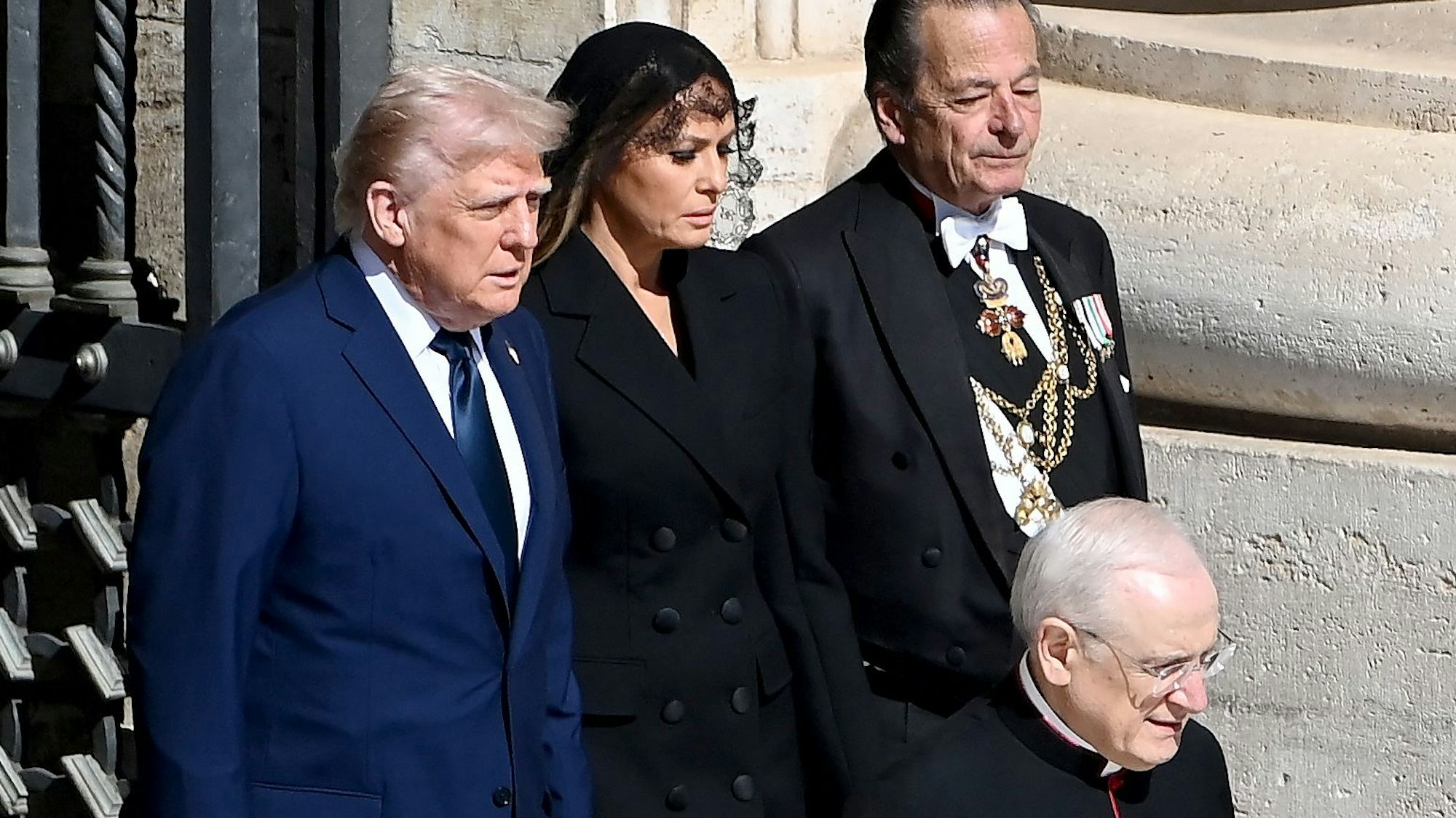 US-Präsident Donald Trump (l) und US-First Lady Melania Trump (m) kommen am 26. April 2025 zur Beerdigung des verstorbenen Papstes Franziskus auf dem Petersplatz im Vatikan.