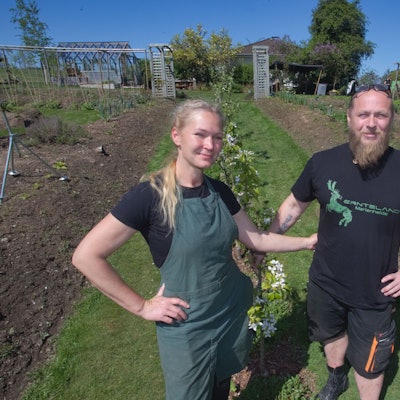Ein Ehepaar steht in ihrem Garten – einem ökologischen Anbauprojekt.