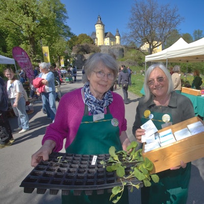 Zwei Damen mit Tabletts in der Hand, Im Hintergrund das Schloss.