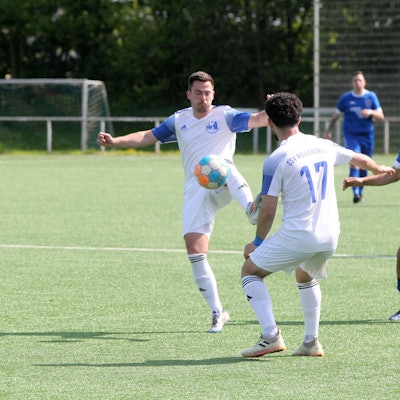 Sven Stanienda nimmt einen Ball an, ein Mitspieler und ein Gegenspieler schauen zu.