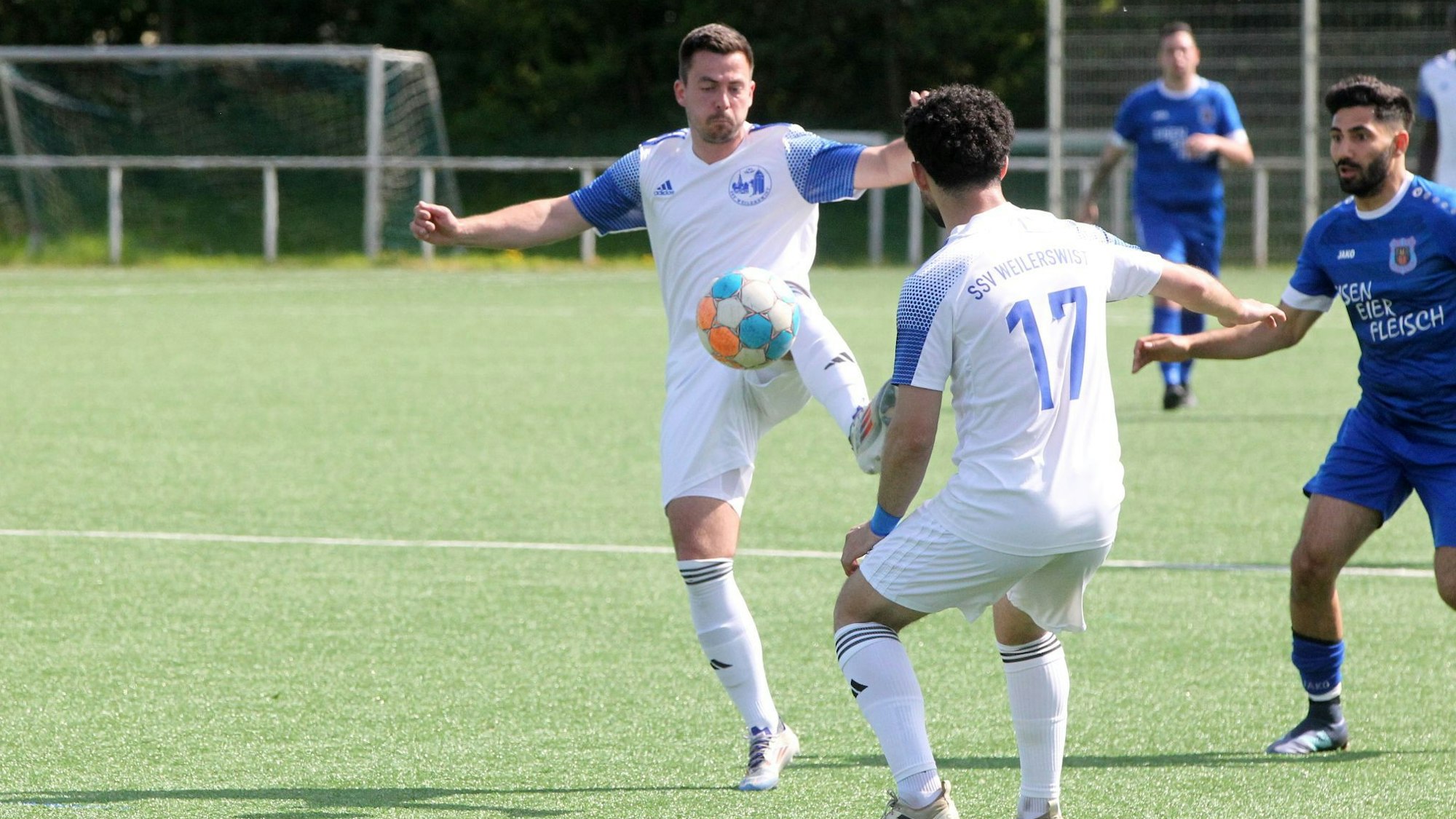 Sven Stanienda nimmt einen Ball an, ein Mitspieler und ein Gegenspieler schauen zu.