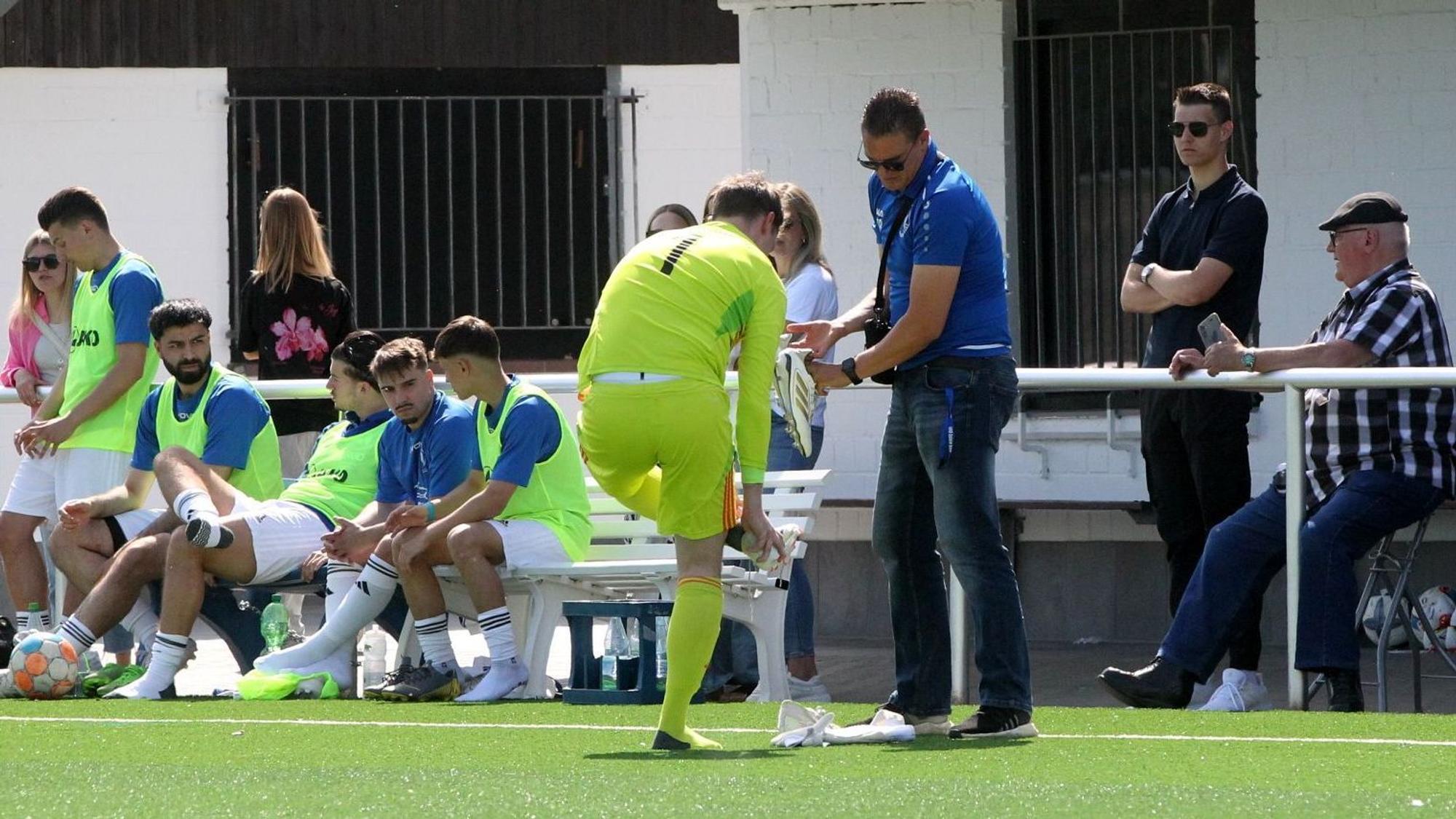 Der Weilerswister Torwart steht am Spielfeldrand und wechselt seine Schuhe.