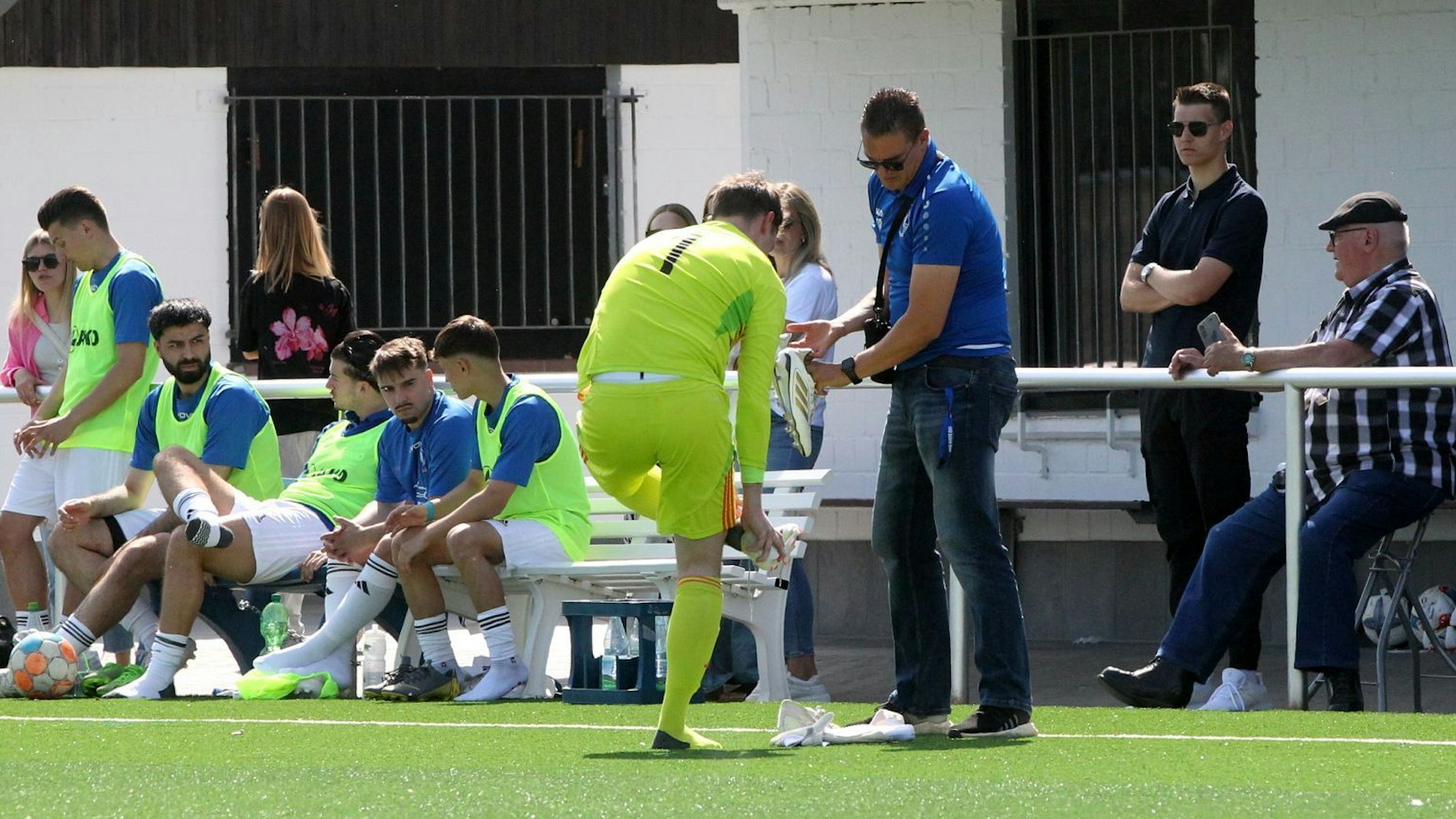 Der Weilerswister Torwart steht am Spielfeldrand und wechselt seine Schuhe.