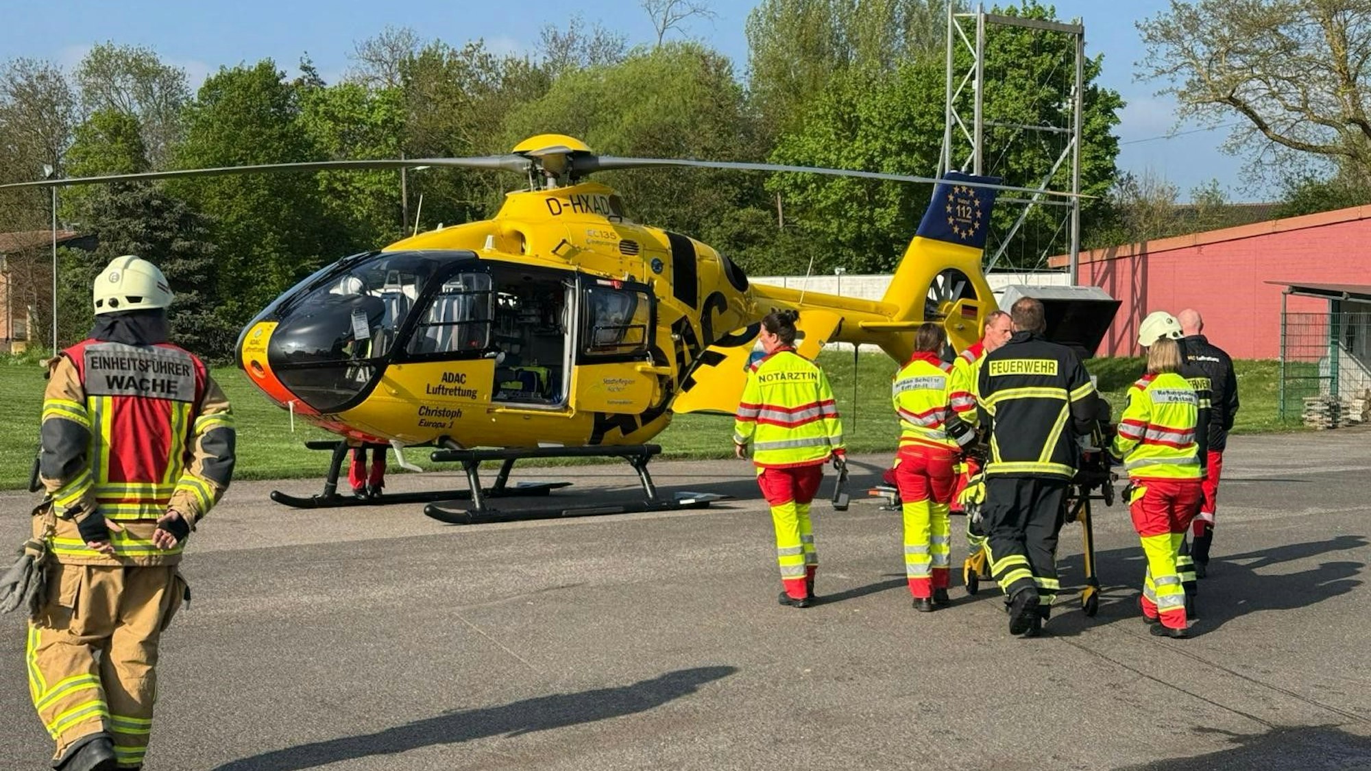 Das Bild zeigt mehrere Personen der Feuerwehr, die einen Mann zu einem Rettungshubschrauber bringen.