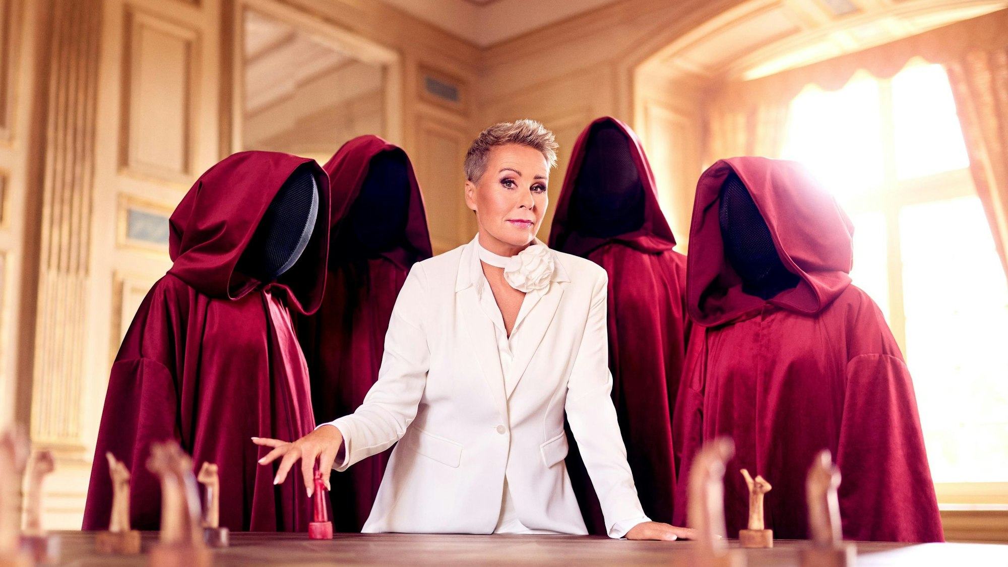 Sonja Zietlow steht in der Schlosskulisse mit vermummten Gestalten.