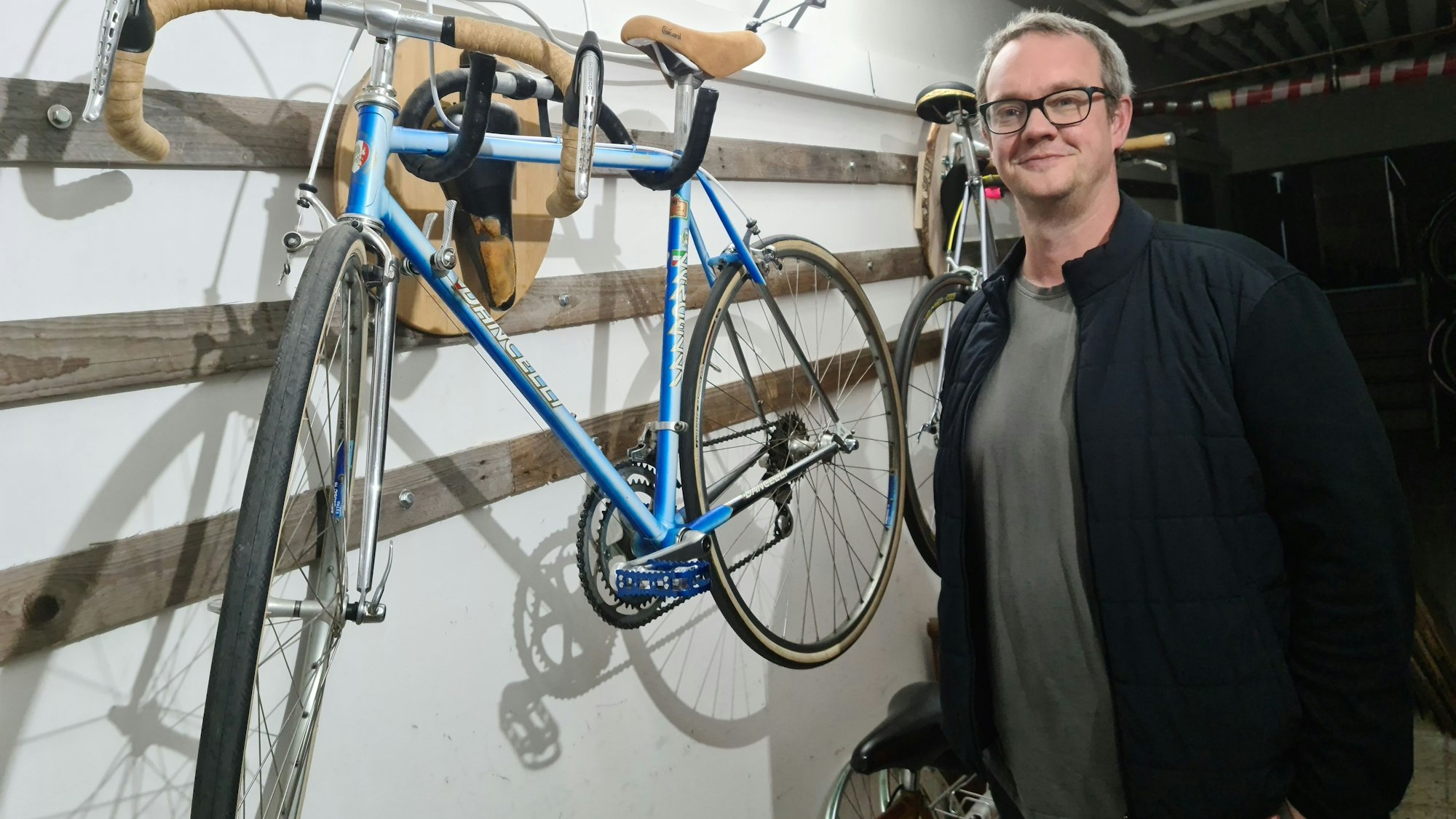 Ein Mann steht neben einem Rad, das an einer Vorrichtung an der Wand hängt.