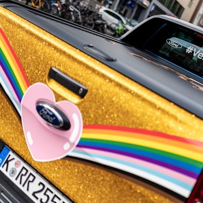 Der in Regenbogenfarben und goldenem Glitter lackierte oder folierte CSD-Raptor.