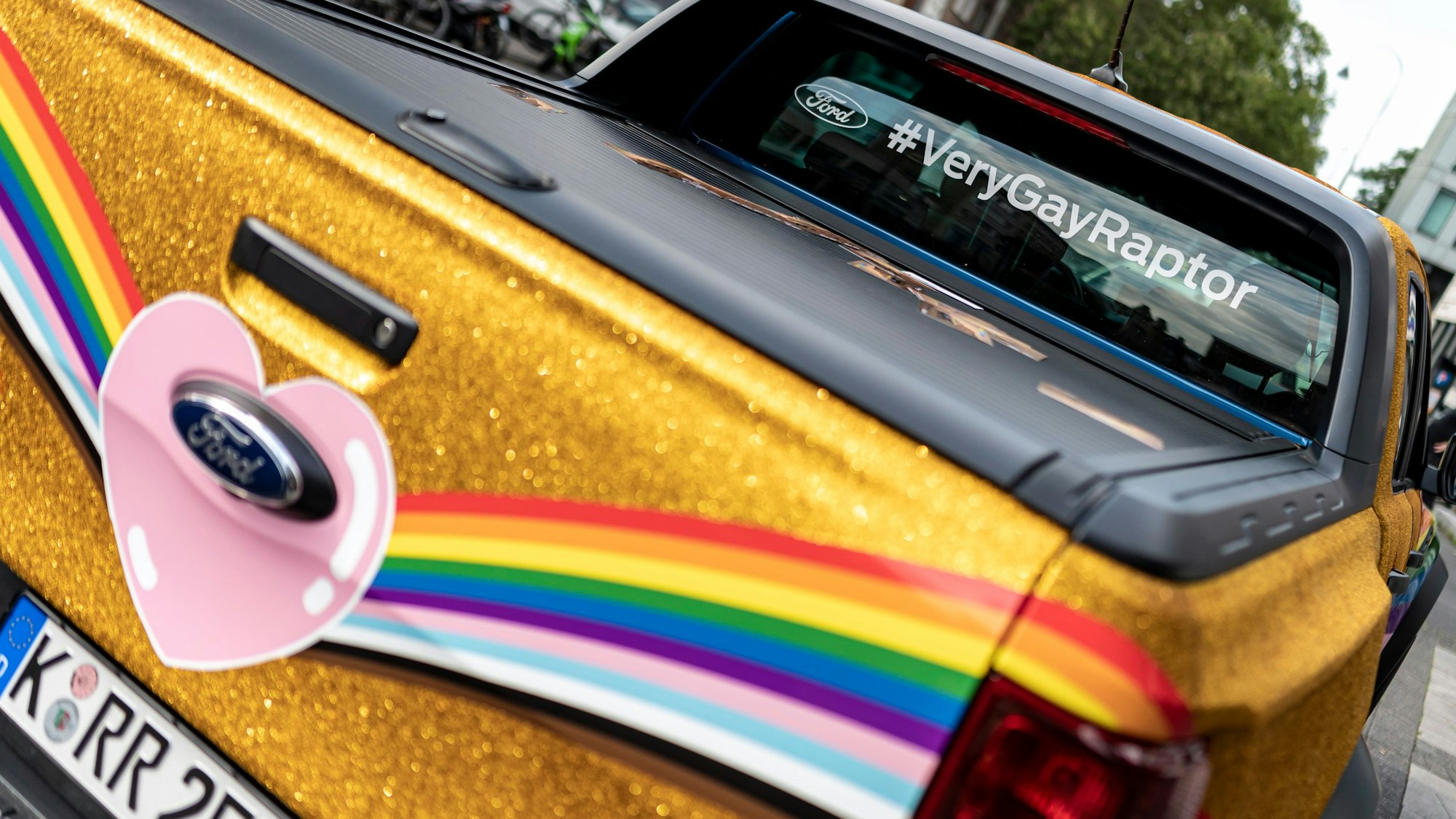 Der in Regenbogenfarben und goldenem Glitter lackierte oder folierte CSD-Raptor.