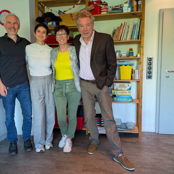 Zwei Männer und zwei Frauen stehen vor einem Regal mit Spielsachen und Kinderbüchern.