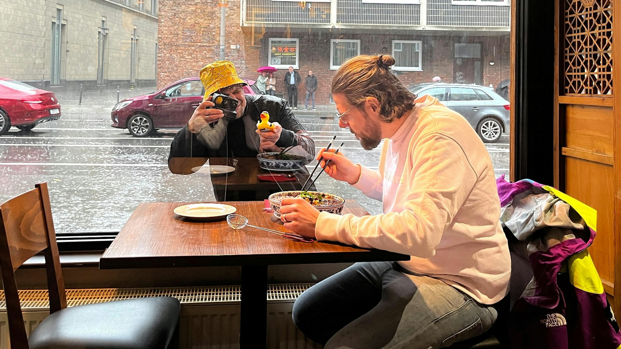 Tim Mälzer (draußen mit Enten-Hut auf dem Kopf und Quietsche-Ente in der Hand) gibt alles, um Philipp Vogel beim Erschmecken des Gerichts im „Great Wall“ aus der Ruhe zu bringen.