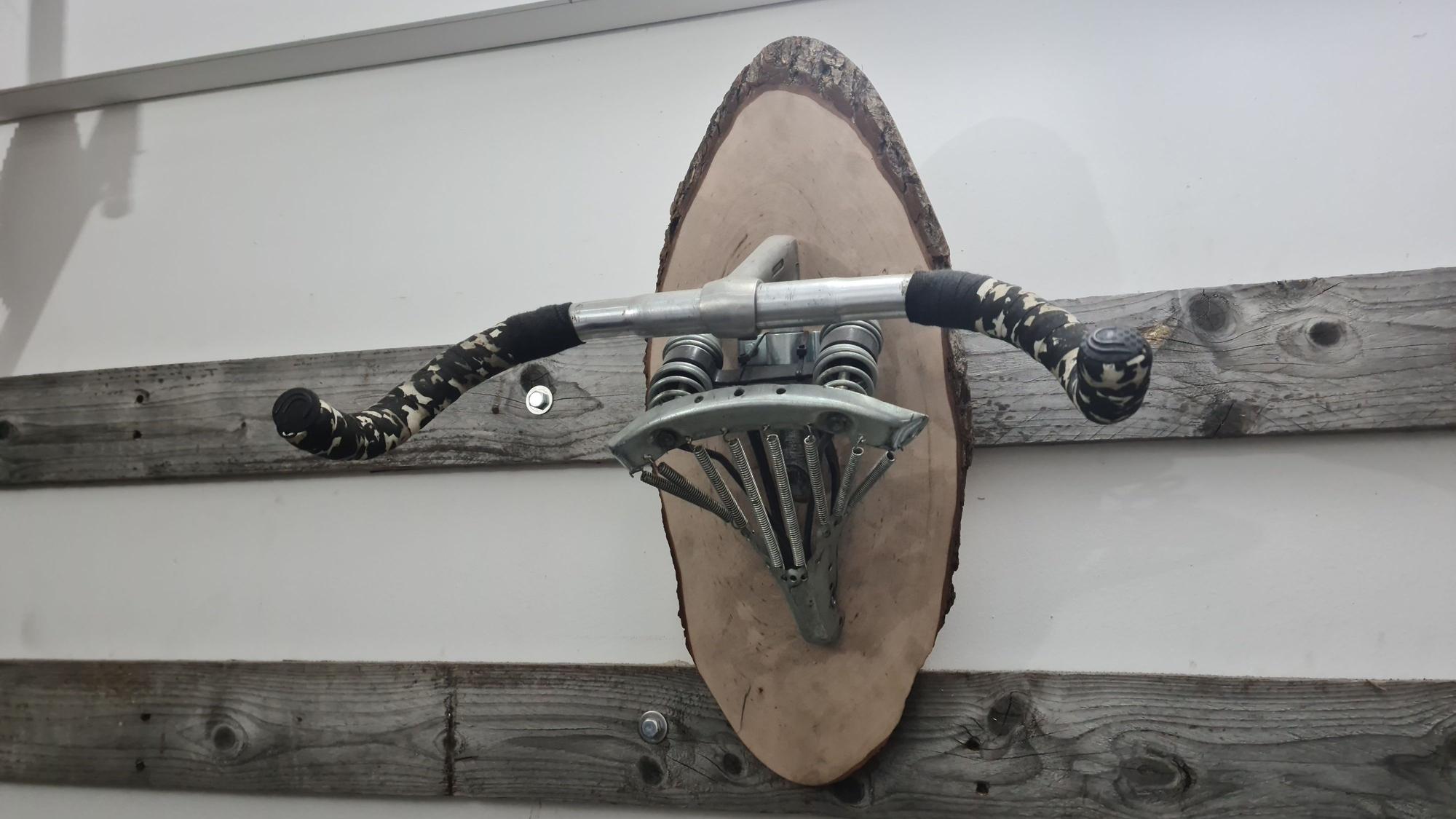 An der Wand hängt ein Lenker, verbunden mit einem Sattel, der als Fahrrad-Aufhänge-Vorrichtung dient.