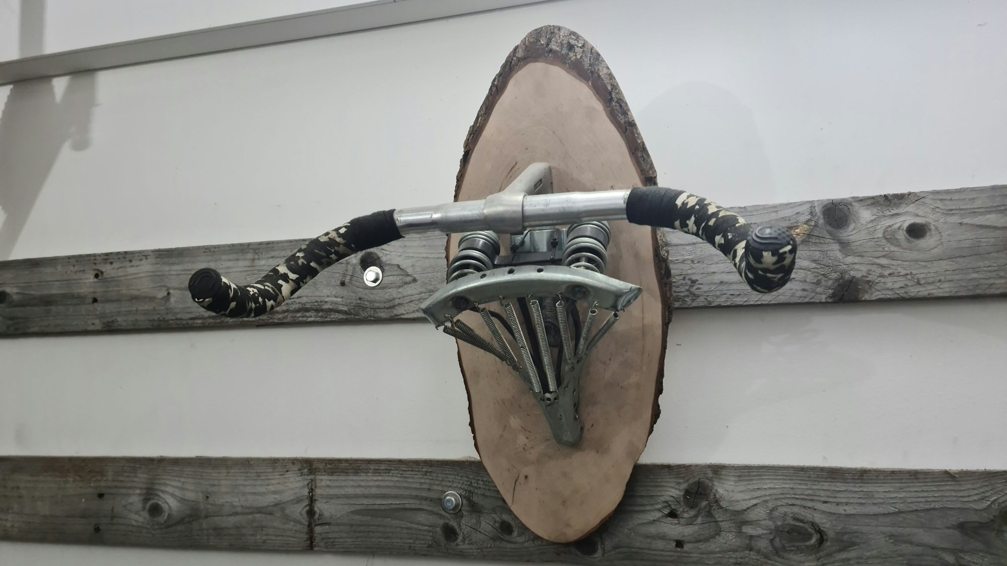 An der Wand hängt ein Lenker, verbunden mit einem Sattel, der als Fahrrad-Aufhänge-Vorrichtung dient.