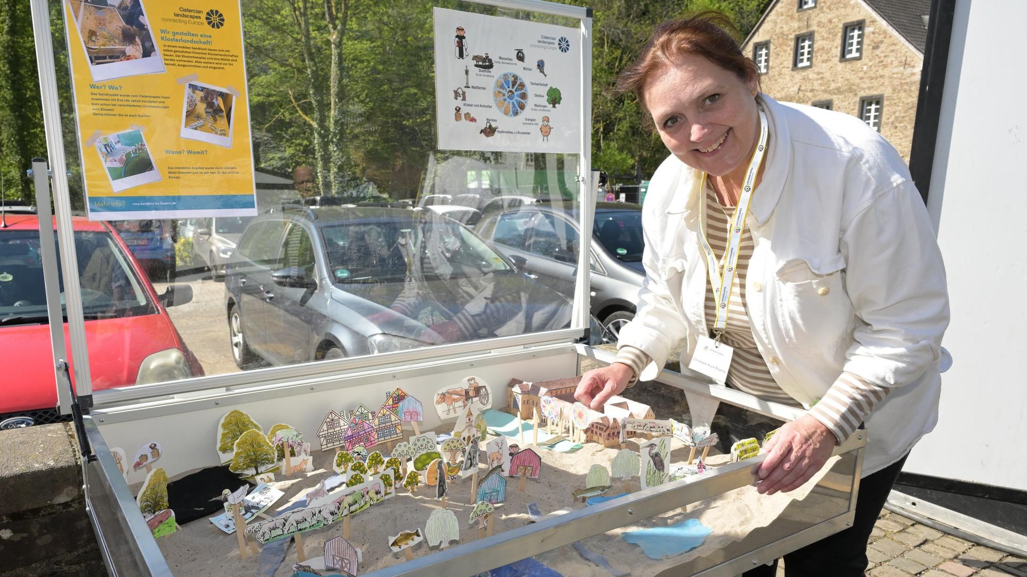 Christiane Huck-Stiasny steht neben einem Miniaturnachbau der zisterziensischen Gesellschaft.