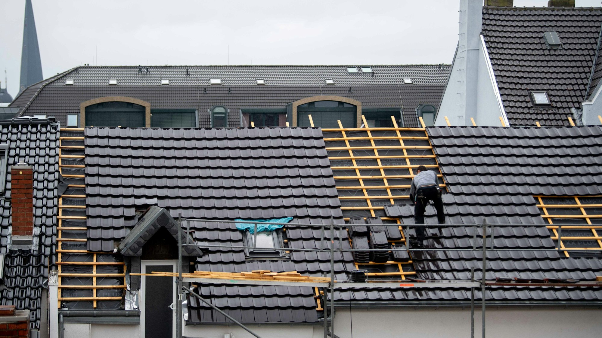Ein Dachdecker deckt im Regen ein Dach in der Euskirchener Innenstadt.