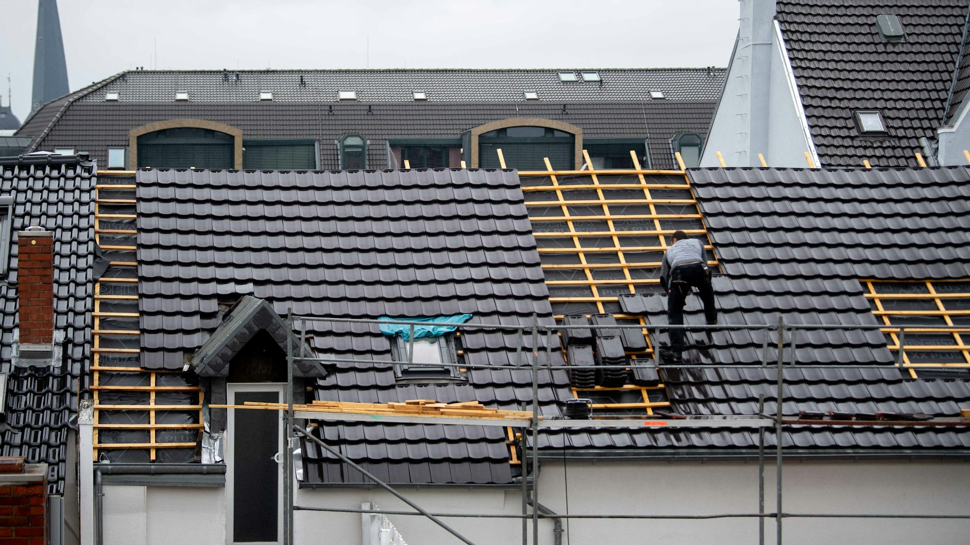 Ein Dachdecker deckt im Regen ein Dach in der Euskirchener Innenstadt.