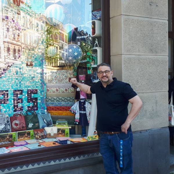 Inhaber Marc Düssel vor seinem reich dekorierten Schaufenster mit der Nippes-Hommage aus Pailletten.