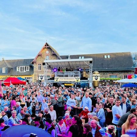 Ein Mann mit Mikrofon steht vor einer Menschenmenge beim Overather Frühling 2024.