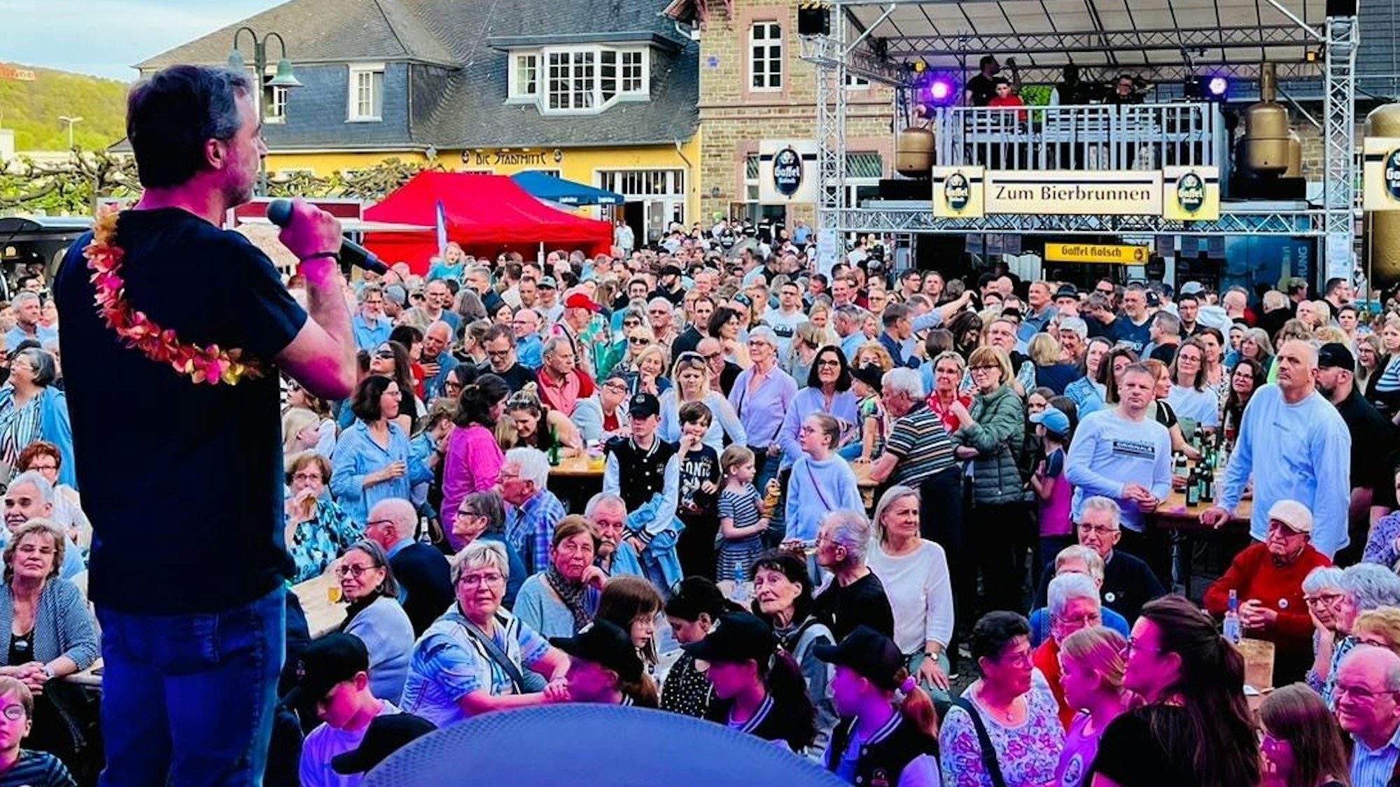 Ein Mann mit Mikrofon steht vor einer Menschenmenge beim Overather Frühling 2024.