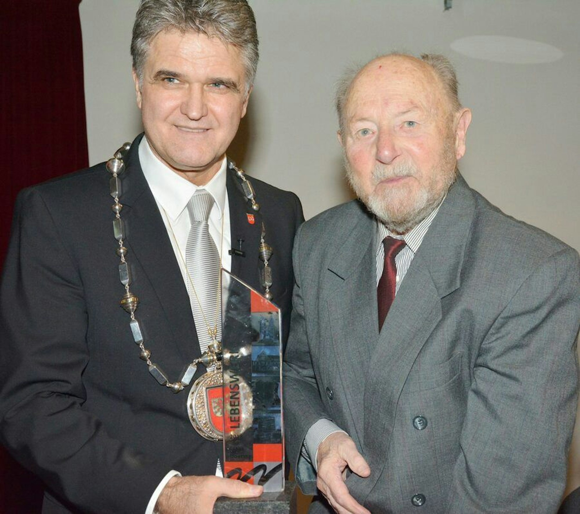 Claus Doering hält neben Bürgermeister Erwin Esser die Ehrennadel der Stadt Wesseling in Richtung der Kamera.