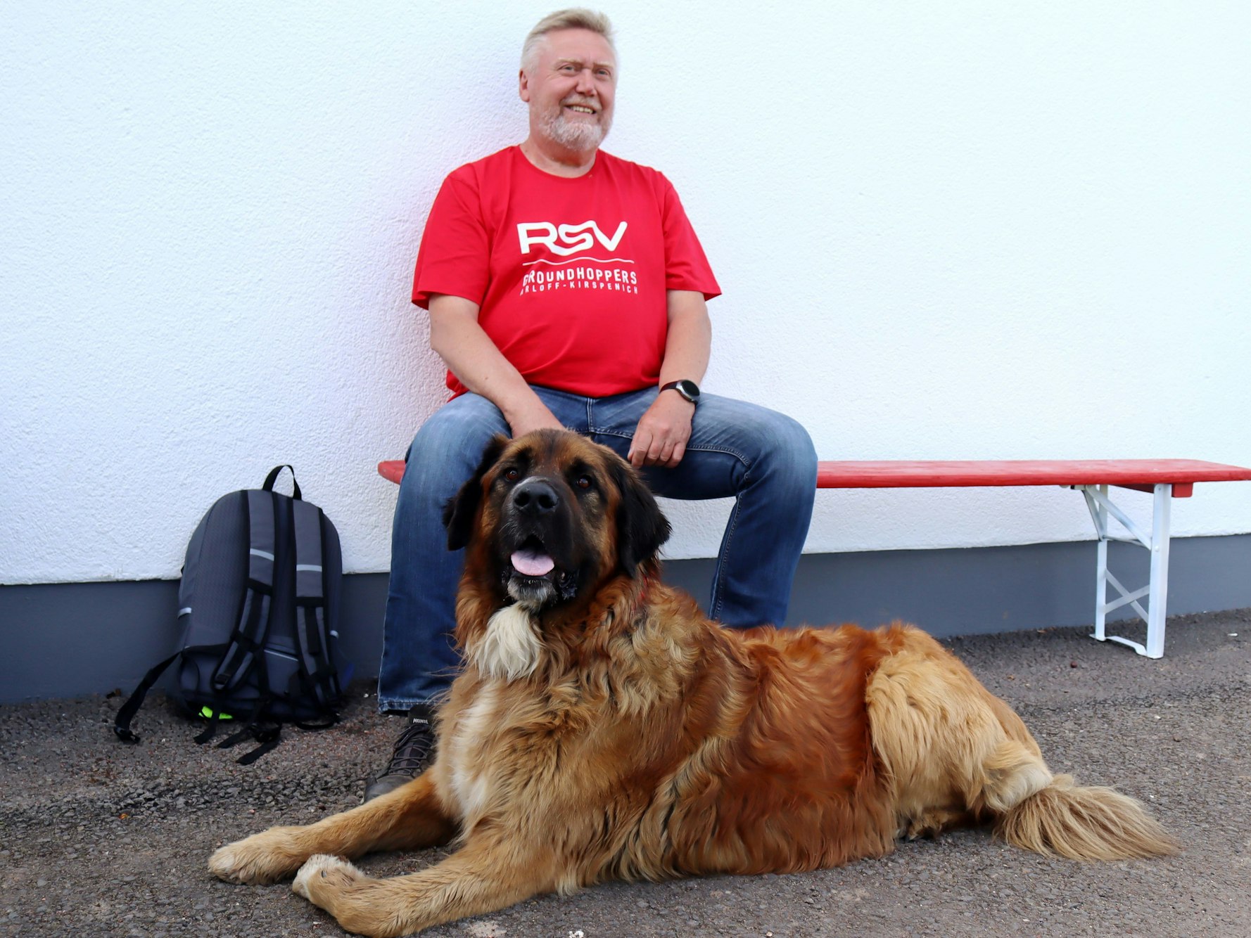Jürgen Großmann sitzt auf der Bank, vor ihm liegt sein Hund, das Groundhoppers-Maskottchen Oskar.