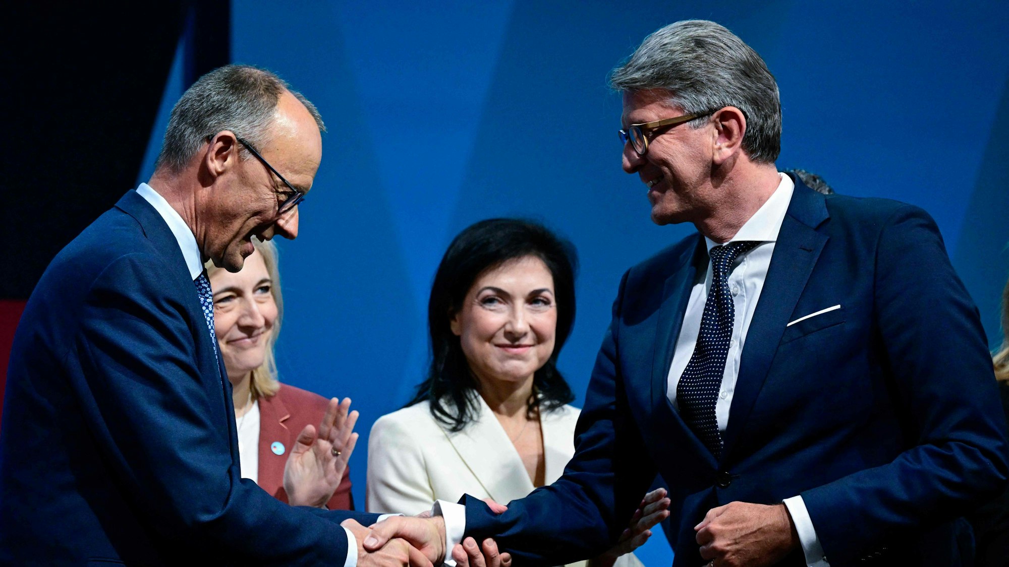 CDU leader Friedrich Merz (L) shakes hands with Wolfram Weimer, designated German Minister for Culture and Media, during the federal committee meeting of Germany's conservative Christian Democratic Union (CDU) party, on April 28, 2025 in Berlin. The committee adopted the coalition agreement negotiated with the social democratic SPD party. (Photo by John MACDOUGALL / AFP)