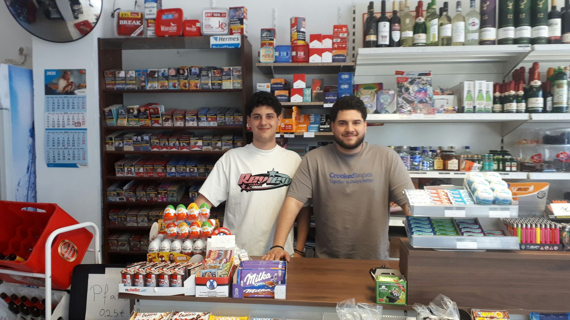 Zwei junge Männer stehen hinter einer Kiosk-Theke.